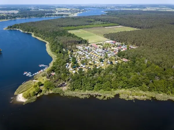 Luftaufnahme eines Campingplatzes am Seeufer mit vielen Wohnwagen, Wald und Wasserlandschaft.