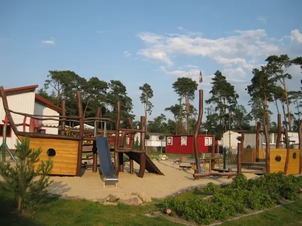 Großer Abenteuerspielplatz mit Holzpiratenschiff, Rutsche und Sandfläche im Freien.