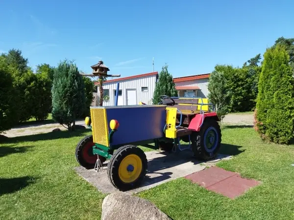 Bunter Oldtimer-Traktor steht auf Rasen vor einem Gebäude an einem sonnigen Tag.